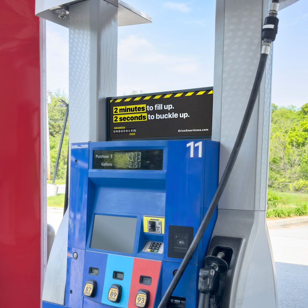 GasTopper_GettyImages-2158635345-mockup2sm Iowa Governor's Traffic Safety Bureau ad atop a gas pump. It is high-contrast black and yellow and reads, "2 minutes to fill up. 2 seconds to buckle up. No one's a safe unbuckled driver. DriveSmartIowa.com"