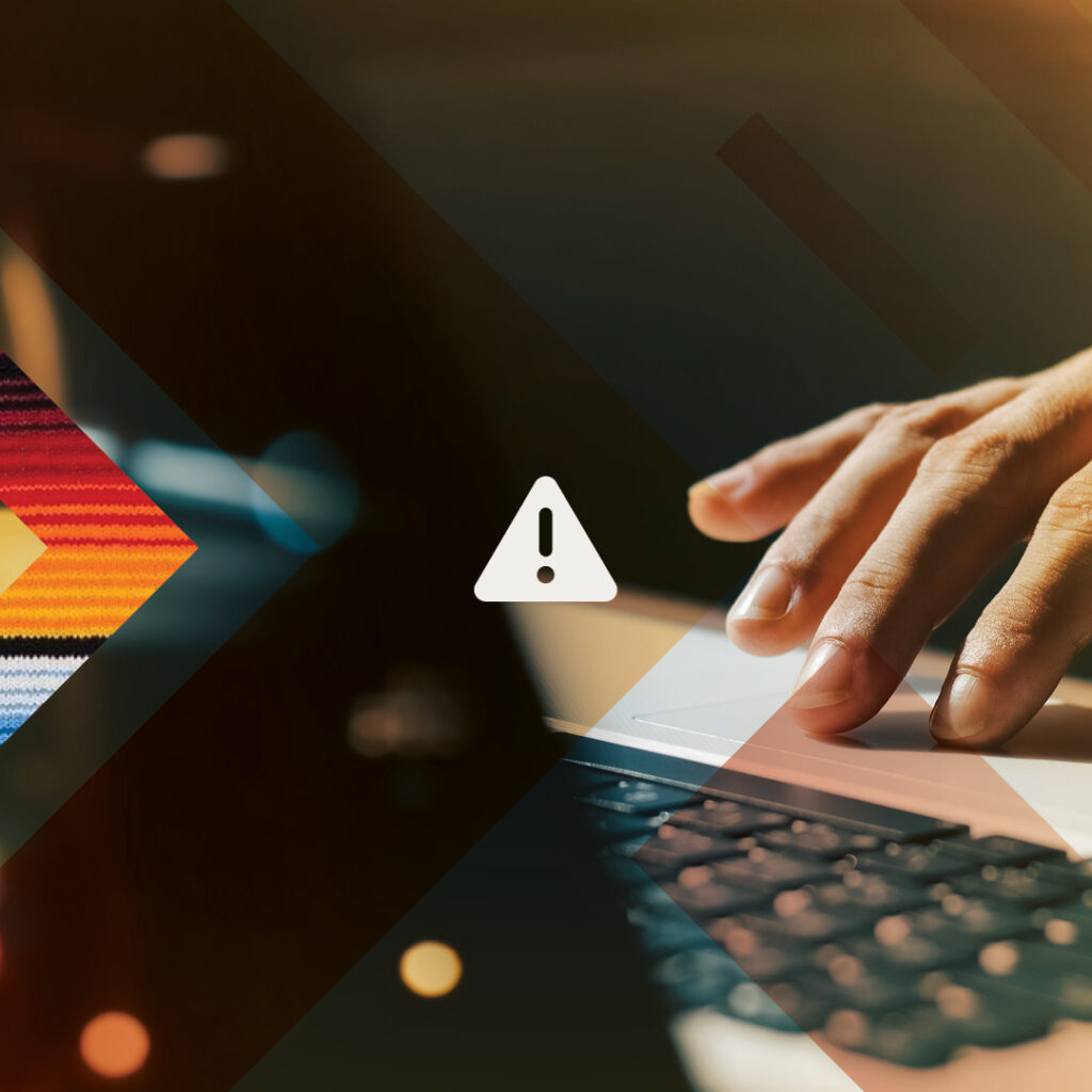 Moody shot of a hand on a laptop trackpad. A white caution icon is superimposed overtop.